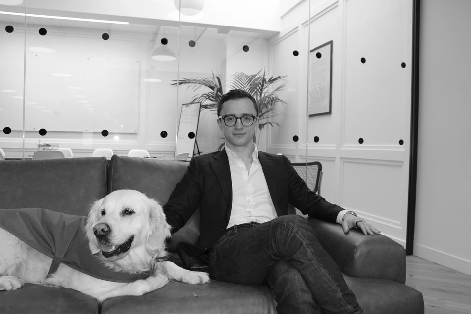Alexis Augier on a sofa in the Vega office, beside Sienna, his golden retriever